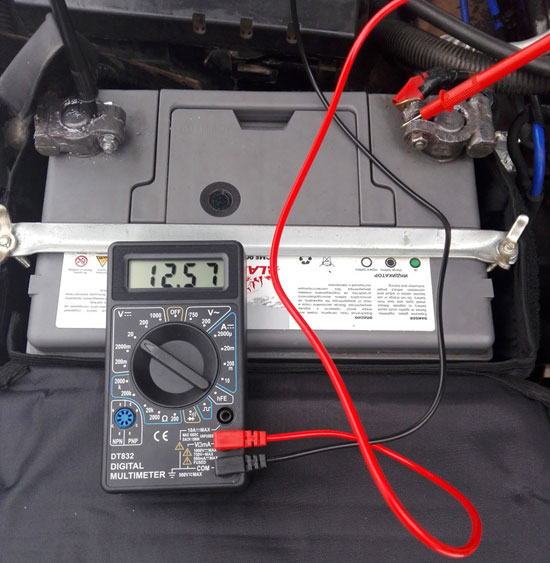 Измерване на напрежението на клемите на автомобилен акумулатор с помощта на цифров мултицет.